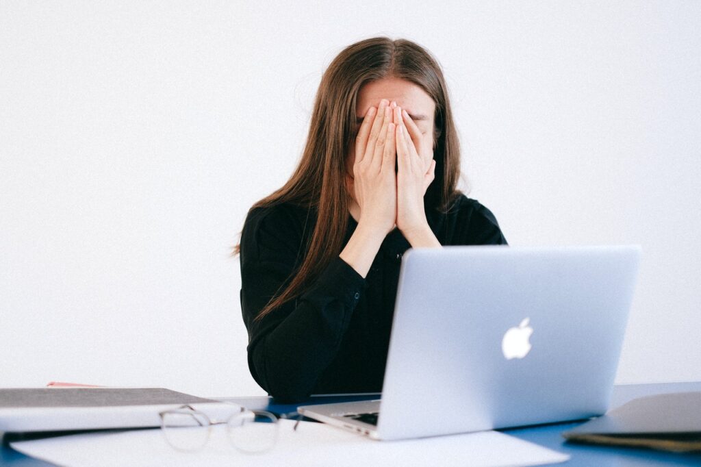 Woman sits at computer looking very stressed out and anxious because of how stress and anxiety affect pain